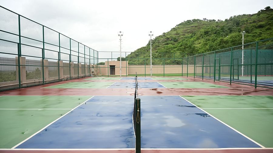 image of the tennis court at club charholi, pune taken from the middle showcasing the net poles