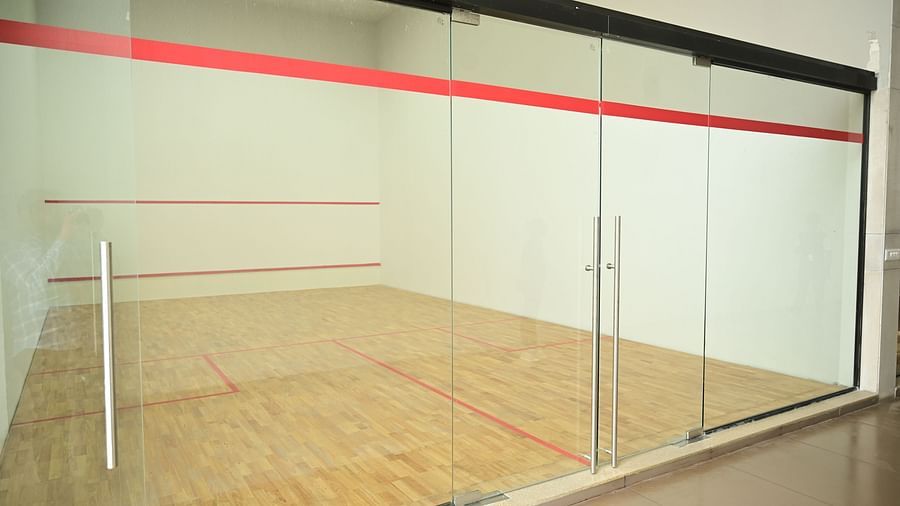 a spacious squash court with tall glass doors at club chrholi, pune
