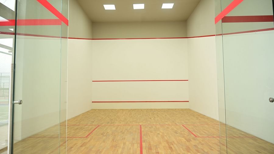 front view image of the squash court with ceiling lights at club charholi, pune
