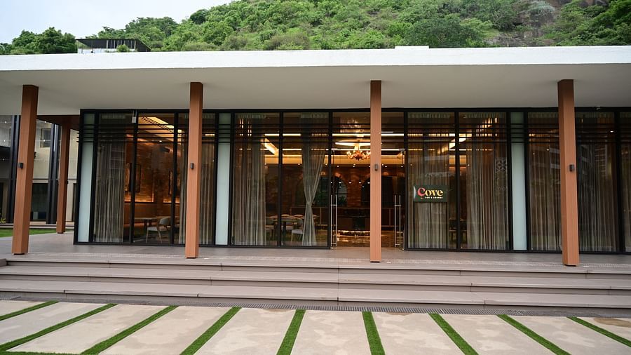 Building with glass doors, columns, and a pathway leading to a hillside.