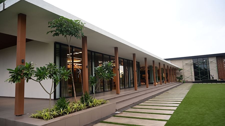 Long building with a covered walkway, glass doors, and a pathway leading to a lawn.