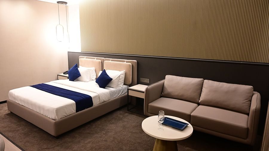 corner view image of the imperial guest suite featuring a double bed and a couch with a coffee table i front of it at club charholi, pune
