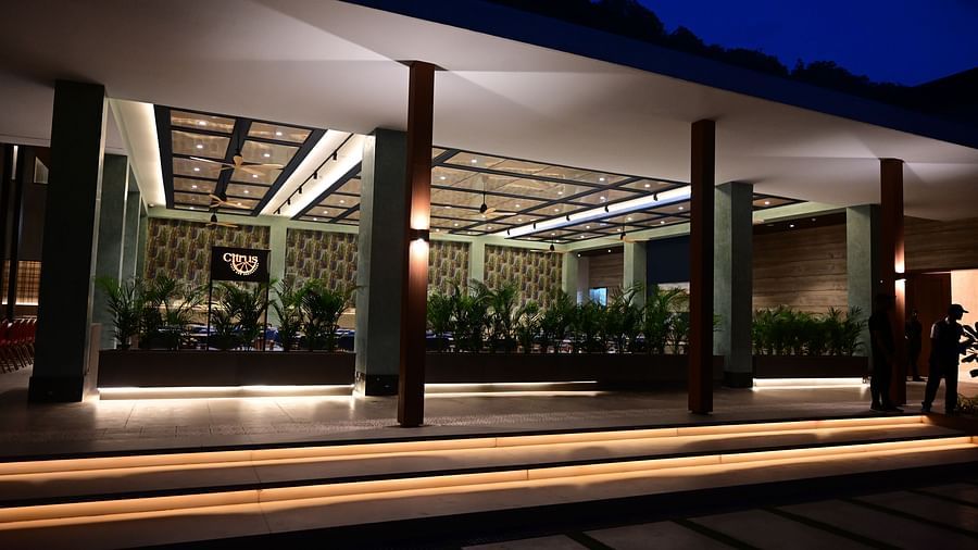 Building facade with illuminated porch and columns at dusk, silhouetted figure in the distance.