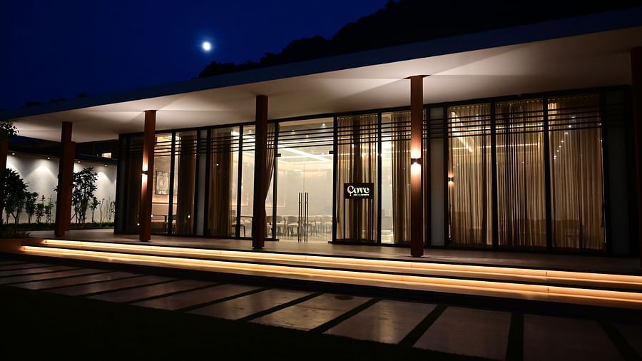 Building with a long porch, glass walls, and a lit pathway at night under a dark sky.