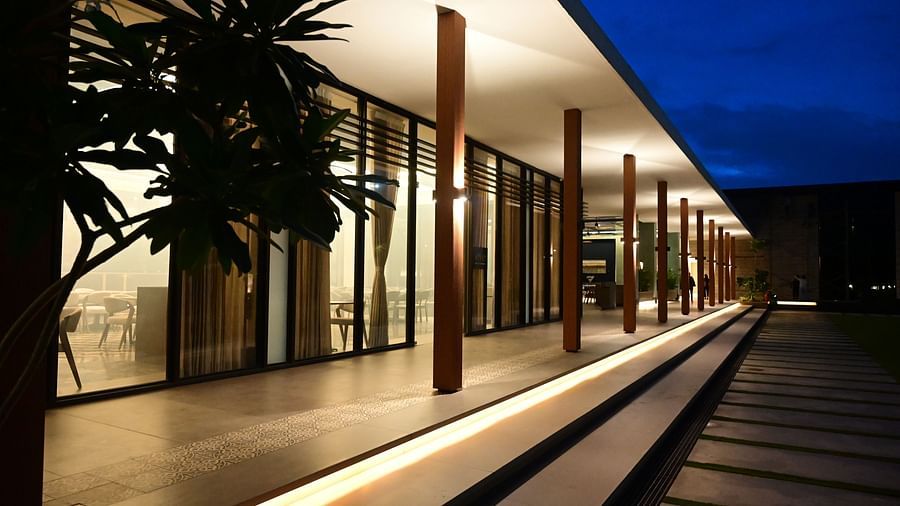 Building with a long, covered walkway, glass doors, and a tree silhouette against the dusk sky.