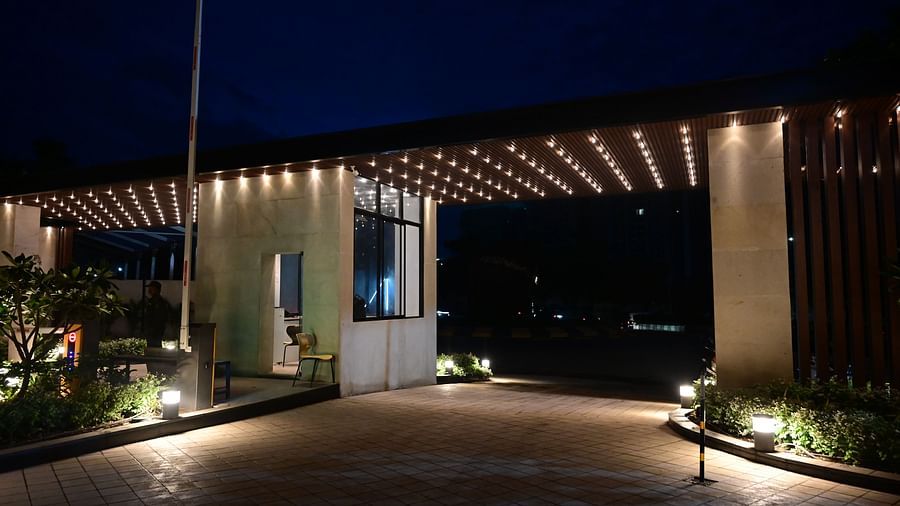 Gated entrance with illuminated pathway and canopy at night, security booth visible.