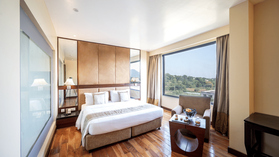 Premium Room at Essentia Luxury Resort & Spa, Udaipur featuring a plush bed and a seating space at its foot by the window