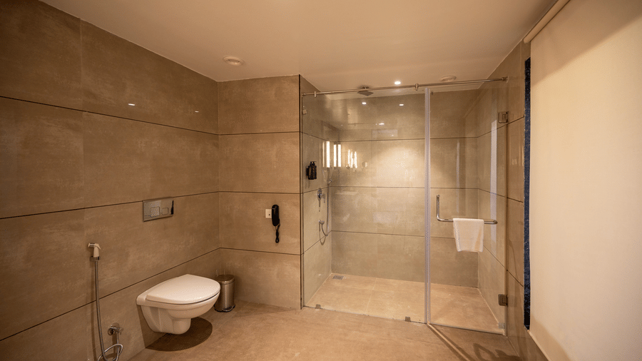 Bathroom of Premium Room at Essentia Luxury Resort & Spa, Udaipur featuring toilet and a showering place separated by glass wall