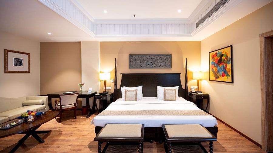 Presidential suite bedroom at Essentia Luxury Resort & Spa, Udaipur, featuring a neatly made bed, a side sofa seater, a coffee table, and modern interior decor