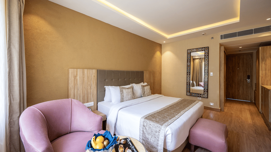 Standard Room featuring a plush bed with ottoman near a seating space with a couch and a coffee table at Essentia Luxury Resort & Spa, Udaipur