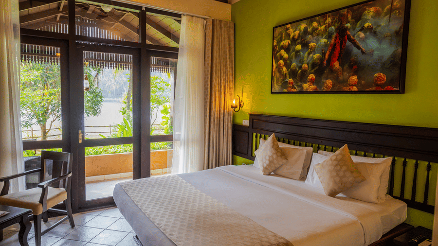 Spacious Lake View Rooms with Private Terrace with a comfortable bed and artwork at Fragrant Nature Kollam.