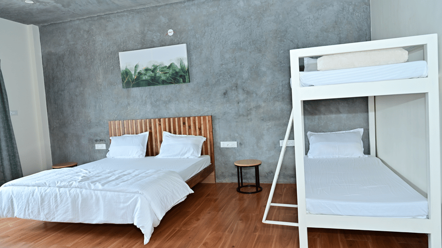 A room at Hilllock Vista Homestay by Aarika Resorts, with a large bed, pillows, spreads, and a bunk bed.