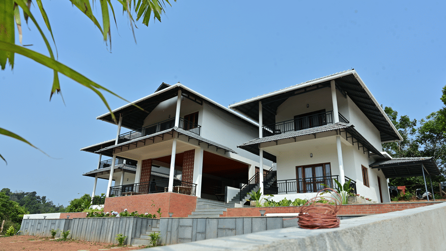 Exterior view of a modern hillside homestay set amidst scenic surroundings.
