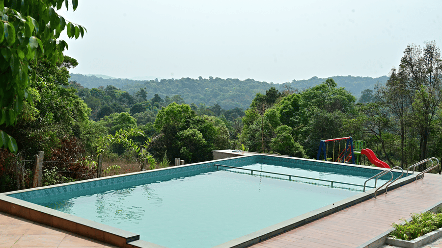 Infinity swimming pool overlooking lush green valleys and scenic hill landscapes.