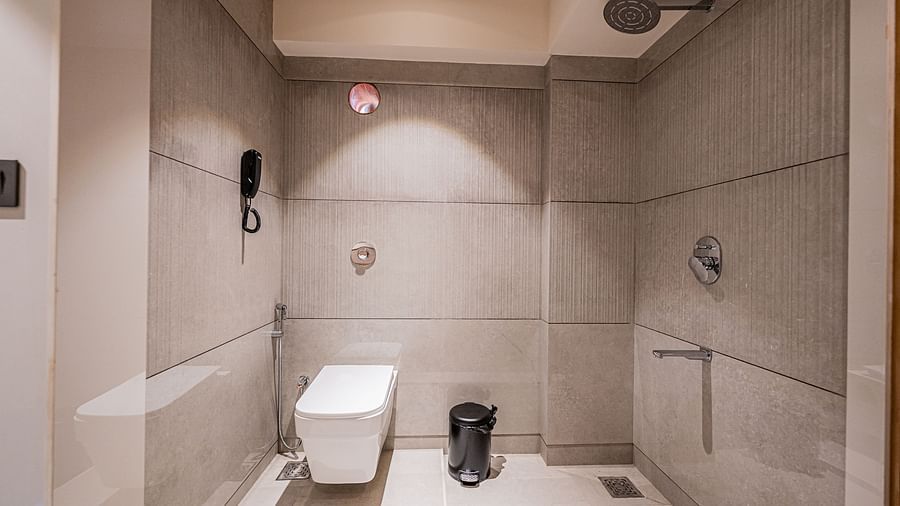 A spacious washroom at Indie Stays Mumbai International Airport, featuring a western toilet and a shower area.