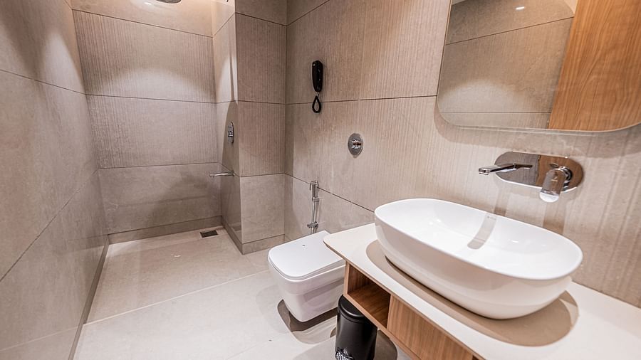 A spacious washroom with a washbasin and a mirror above it, with a shower area towards the end at Indie Stays Mumbai International Airport.
