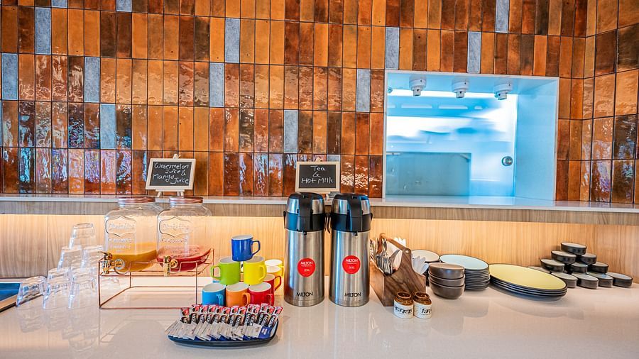 A close-up view of the kitchen counter at Indie Stays Mumbai International Airport, with cups, bottles, and essentials neatly placed on top.