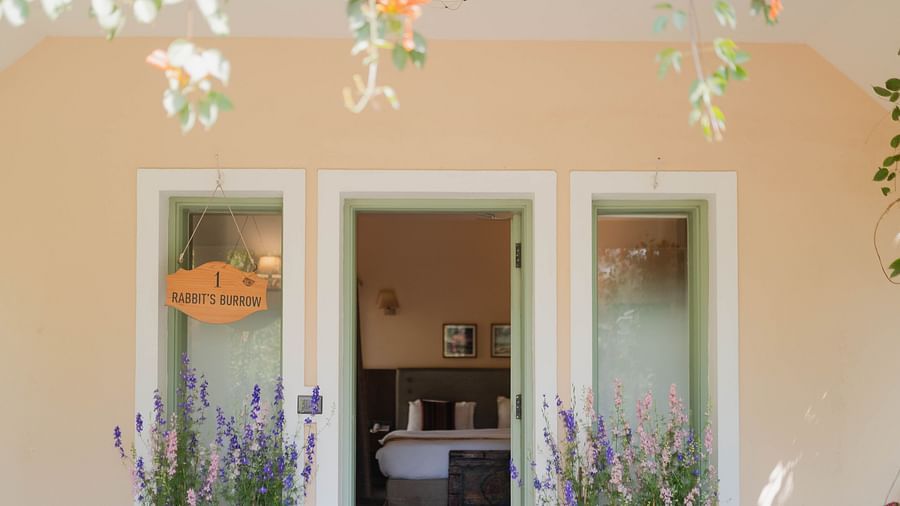 Exterior view of a Karma Chalets unit with two doors, potted plants, and hanging decor.