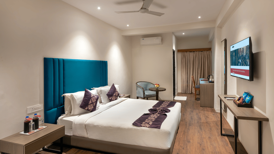 Lords Eco Inn Executive bedroom with a large bed, a headboard, a ceiling fan, and simple wooden furniture.