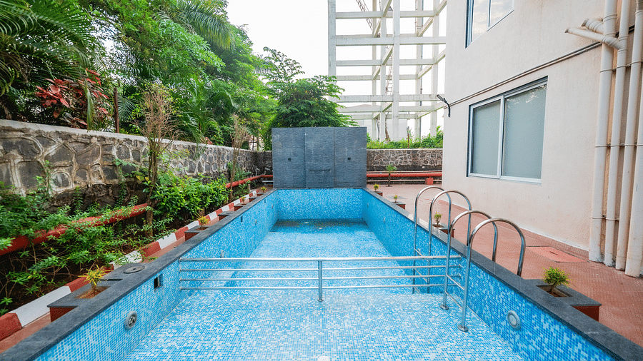An outdoor swimming pool surrounded by greenery and a well-maintained pathway at Lotus Leaf Boutique Hotel.