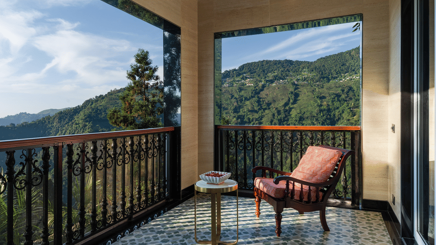 Covered private balcony with armchair looking out onto green mountain slopes at Mayfair Manor, Jungpana.