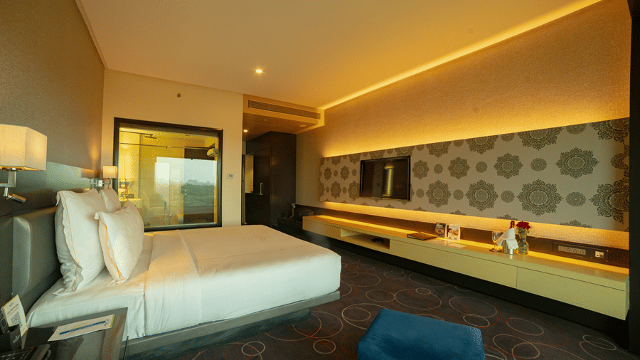 Luxury hotel room with modern lighting and blue seating at Narayani Heights Hotel & Resorts, Ahmedabad.