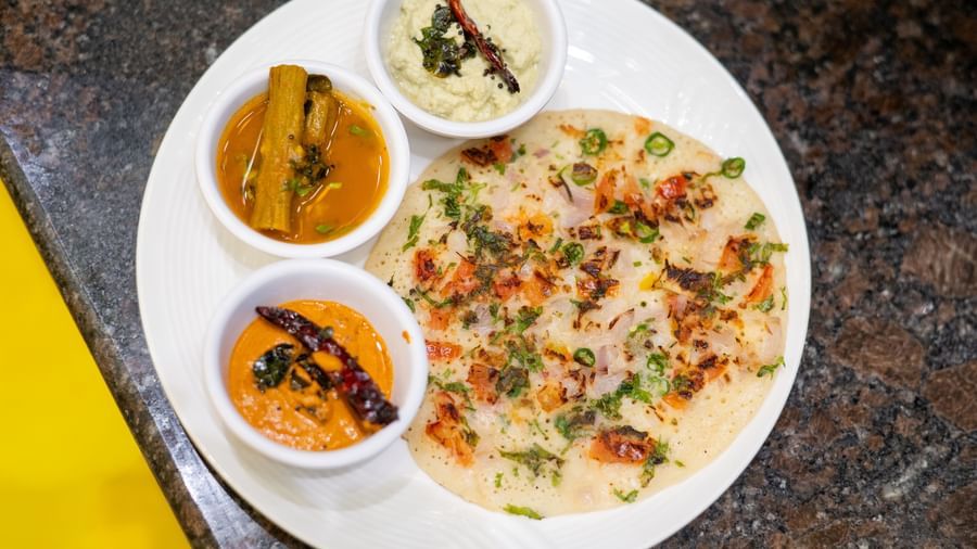 An uttapam is served with a small bowl of sambar and two varieties of chutney at Pravasa Stay, Shirdi.