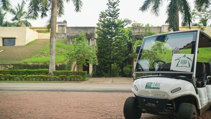 An internal transfortation buggy in Vedic Village Spa Resort stationed against a backdrop of greenery.