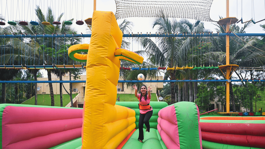 Outdoor inflatable adventure play zone at Vedic Village Spa Resort featuring bright orange and yellow inflatable structures with palm trees in the background.