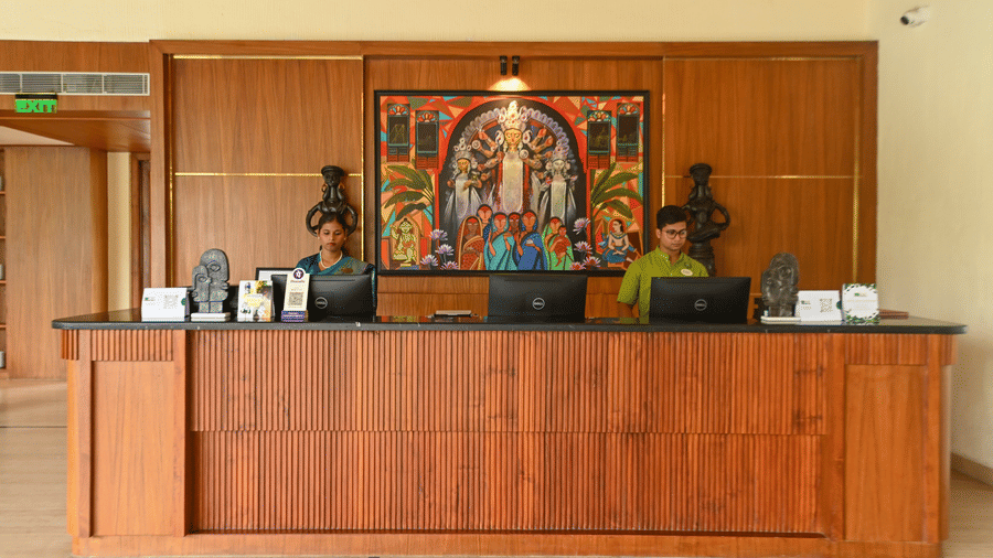 Reception desk at Vedic Village with a long desk, people working, and a wall frame.