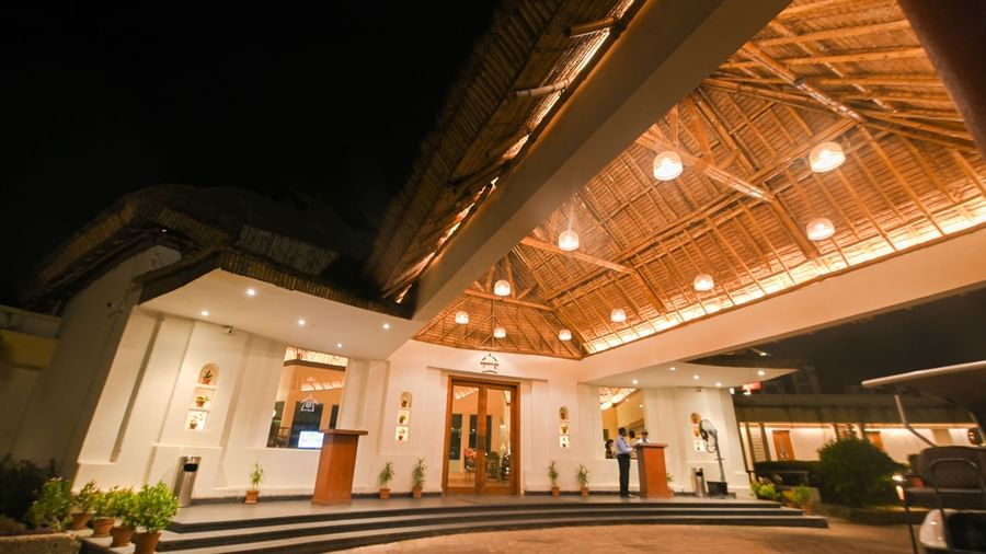 The entrance of Vedic Village Spa Resort featuring an illuminated path way leading to the reception and staff on duty.