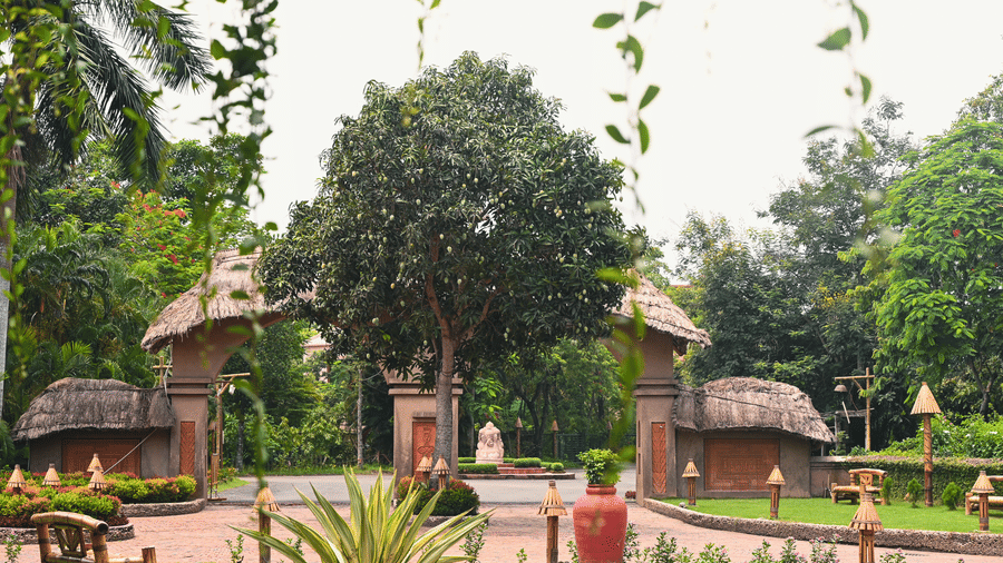 Reception entrance at Vedic Village with trees, plants, and small lawn.