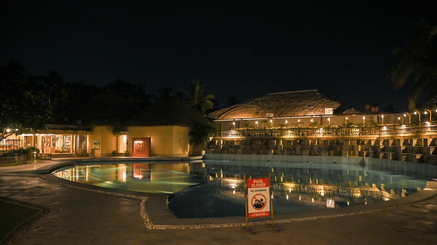 An illuminated pool with cottages in the backdrop at night | Vedic Village