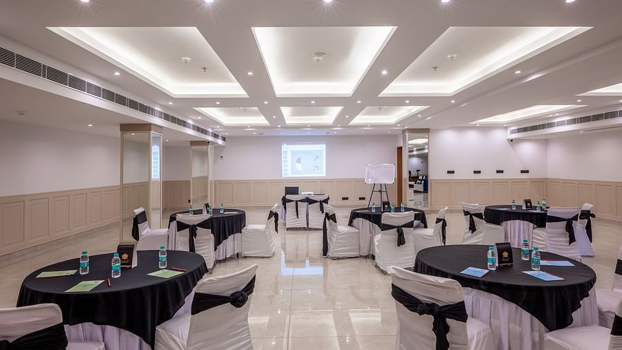 Overview of Maahira Conference room at Vishranti Hotel dehradun with chairs and tables covered in black and white cloth and ambient lighting