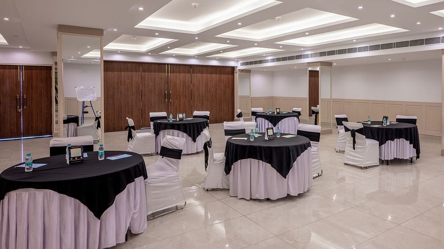 Side shot of Maahira Conference room at Vishranti Hotel dehradun with chairs and tables covered in black and white cloth and ambient lighting