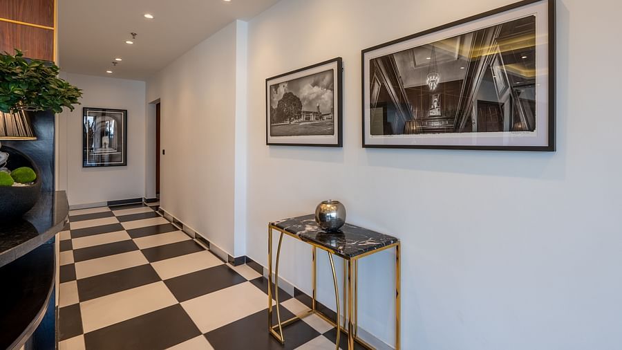 A well-lit interior of a  corridor, furnished with a mix of paintings and a table. - Vishranti Hotel Dehradun