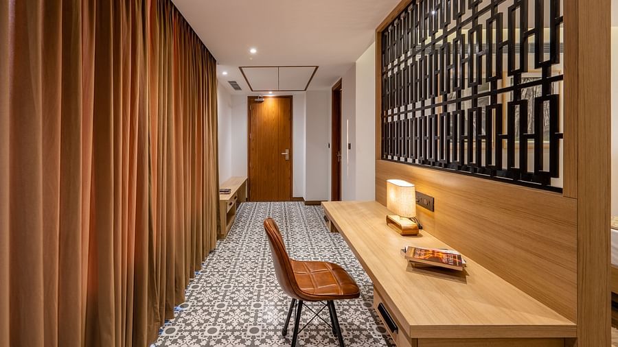 Living area of a suite at Vishranti Hotel, Dehradun featuring a work desk, chair and a metal frame window.
