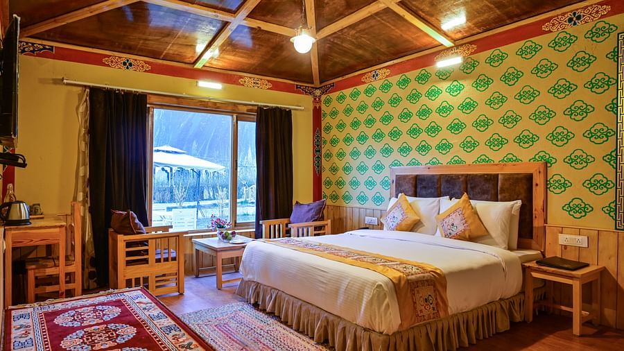Premium Cottage in White Sands Resort, Ladakh, includes a king size bed, a seating area, and patterned wallpaper.