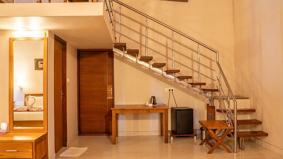 Attic Villa features a staircase leading to a loft area, along with a desk and television | Woodstock Resorts, Coorg