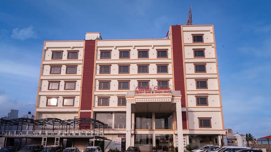 Front view of Clarks Collection Somnath building with facade, multiple floors, parked cars, and a clear blue sky background.