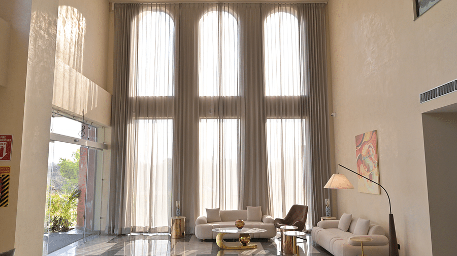A high-ceiling lobby, brightly lit by tall arched windows covered with sheer curtains, with a seating area arranged in the centre of the room. - Clarks Safari Haridwar
