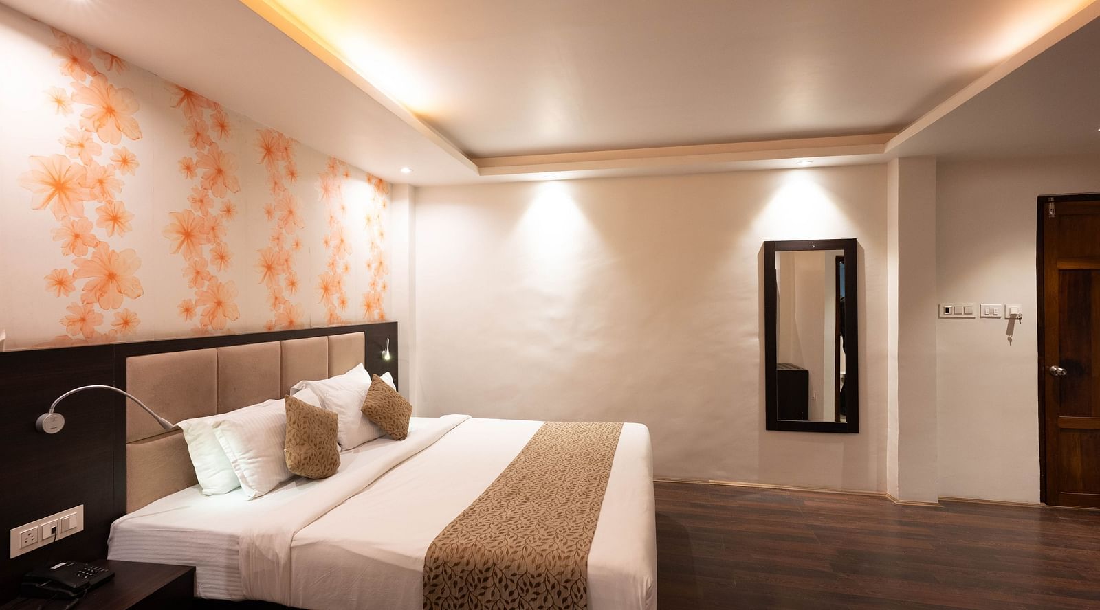 A bedroom featuring a large mirror and floral-designed wallpaper at Avianna Hungry Jack, Gangtok.