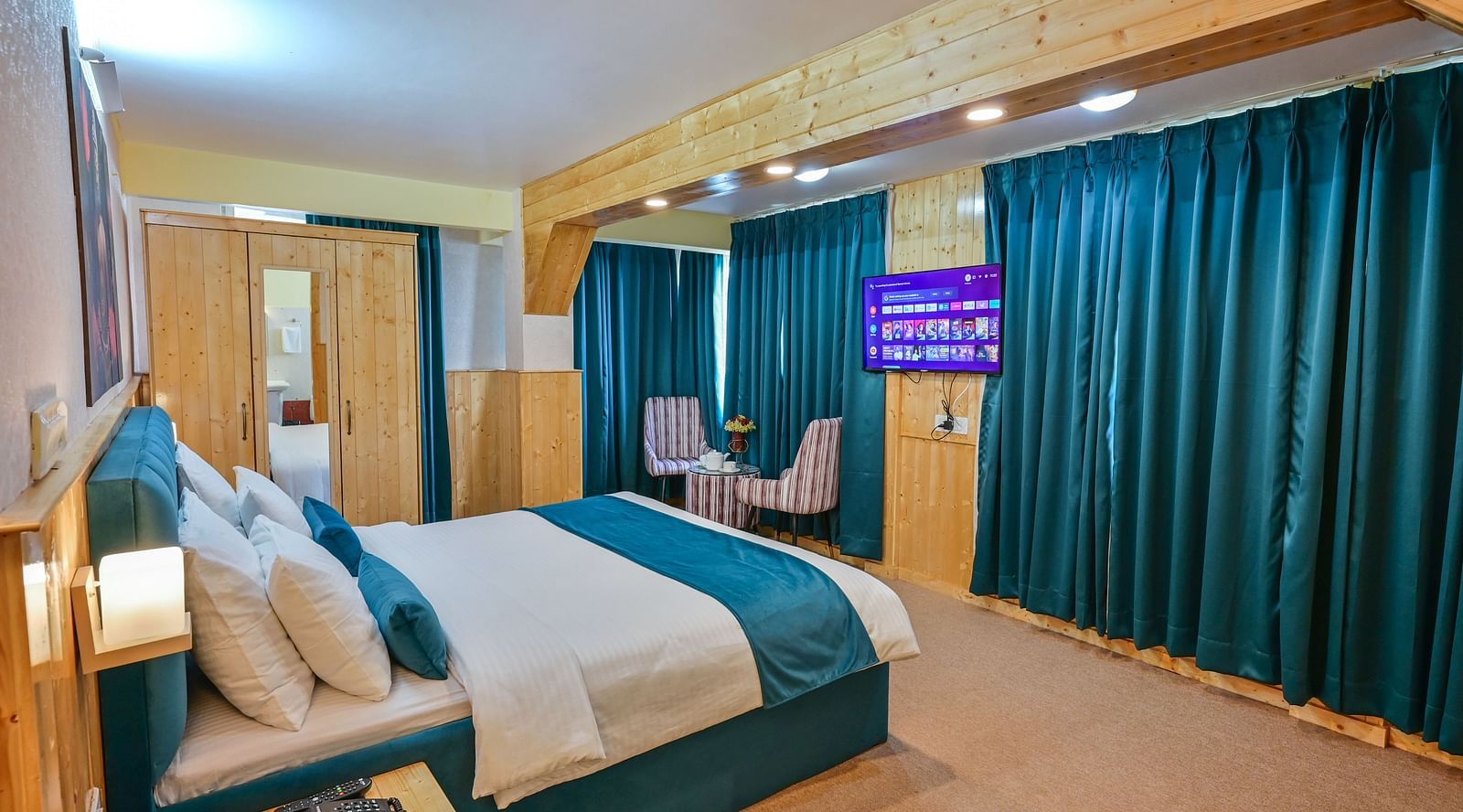 Premium room featuring a king sized bed, wall mounted television, windows with curtains, and warm lighting at Avianna Seven Seas, Darjeeling5