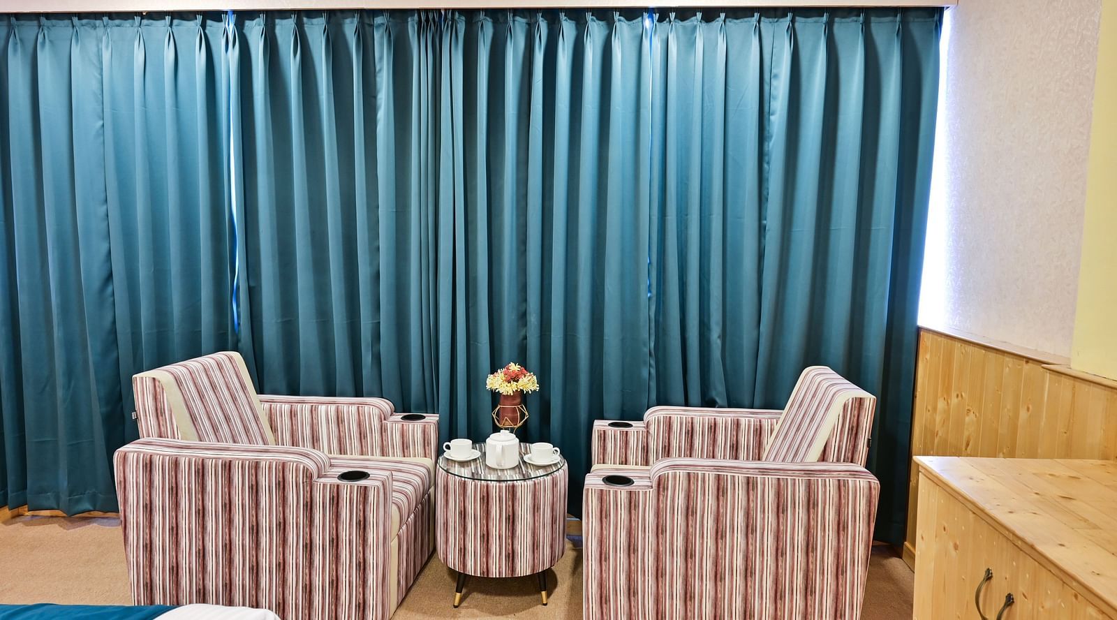 The suite features a spacious bed, large windows stretching along one side of the room, comfortable cushioned furniture, and warm lighting at Avianna Seven Seas, Darjeeling3