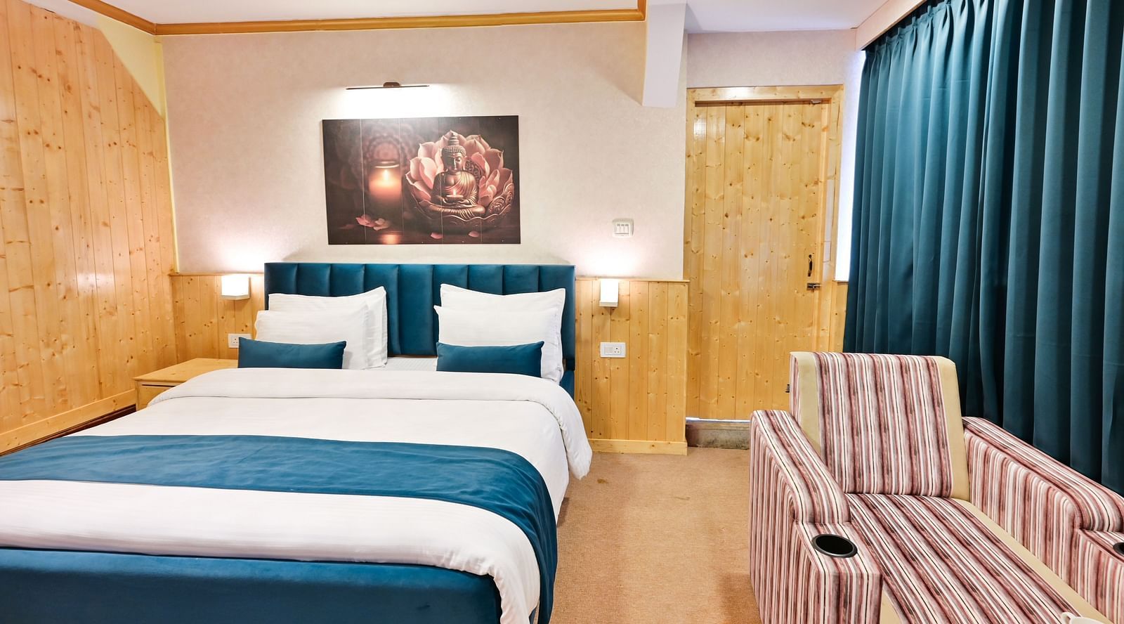 The suite features a spacious bed, large windows stretching along one side of the room, comfortable cushioned furniture, and warm lighting at Avianna Seven Seas, Darjeeling4