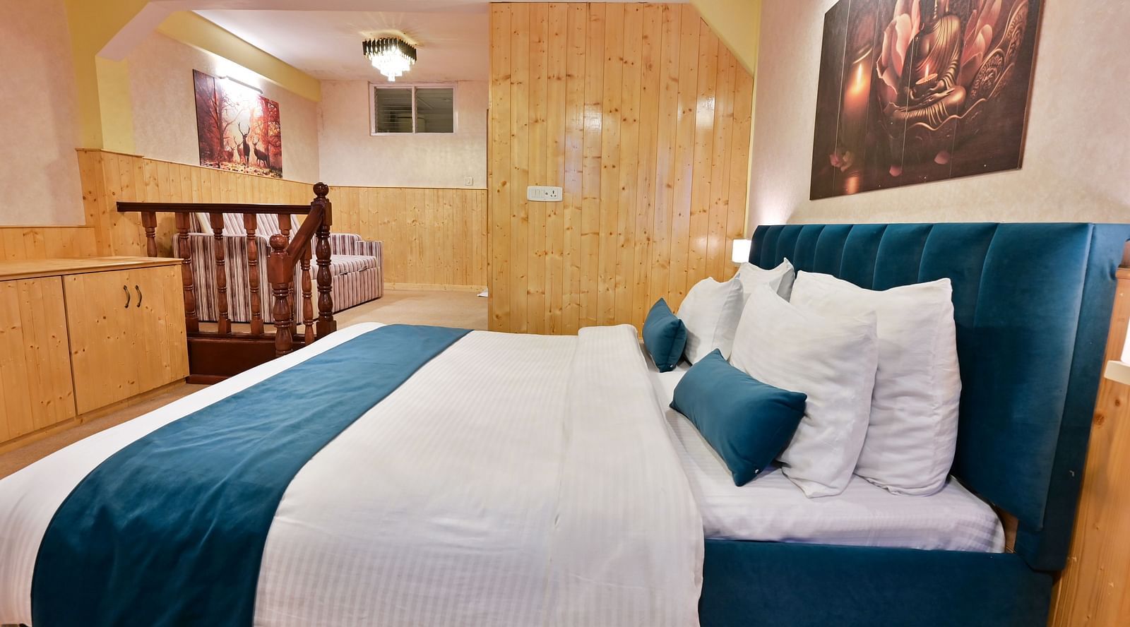 The suite features a spacious bed, large windows stretching along one side of the room, comfortable cushioned furniture, and warm lighting at Avianna Seven Seas, Darjeeling5