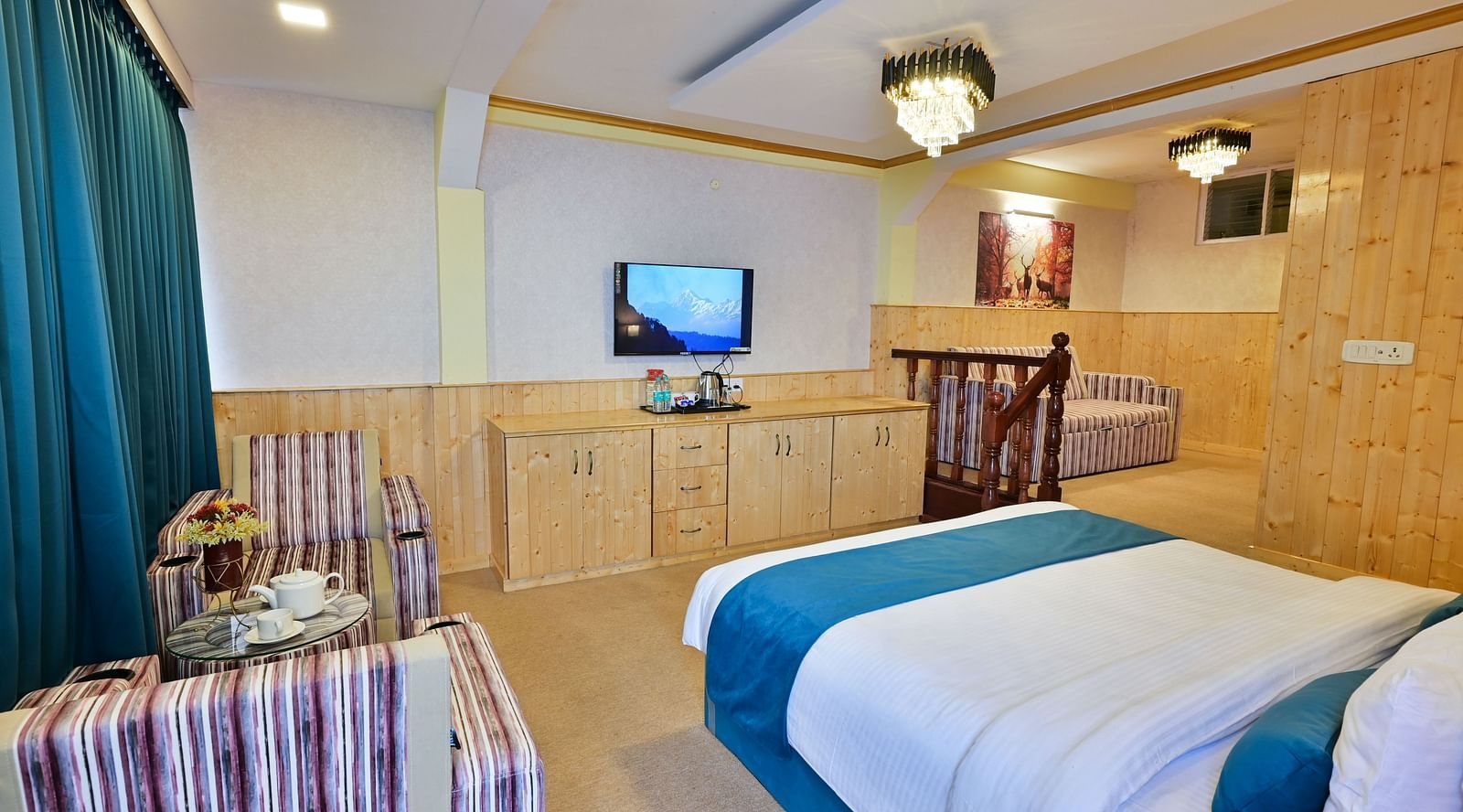 The suite features a spacious bed, large windows stretching along one side of the room, comfortable cushioned furniture, and warm lighting at Avianna Seven Seas, Darjeeling6