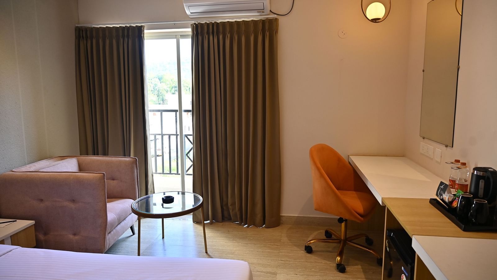 Premium room corner with a chair, a small glass table, and a desk near a sliding door that opens to a private balcony at TGI Livancia Hillside