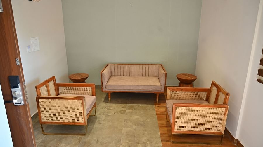 Sitting area with sofas, wooden chairs with cane detailing, and round wooden tables, arranged in a cosy layout at TGI Livancia Hillside