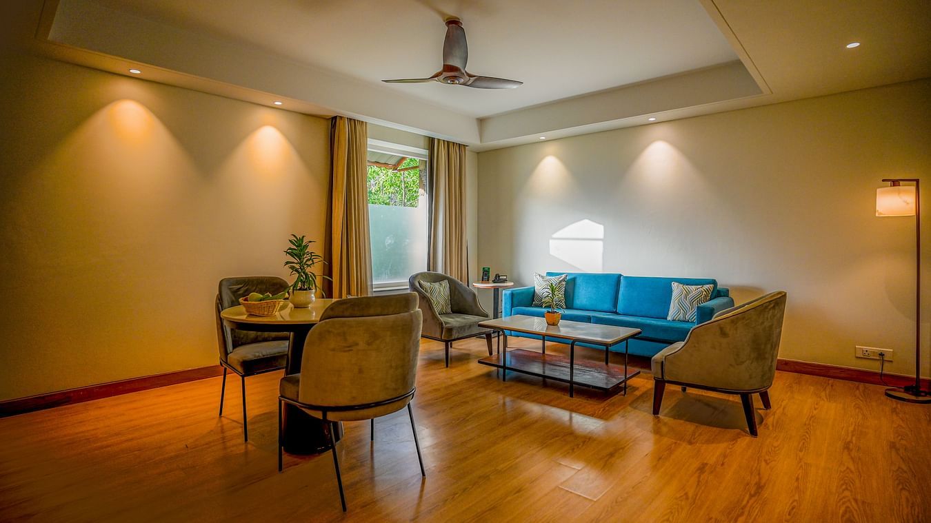 Similar to the previous image, this view shows a slightly different angle of the hotel suite with a round dining table and three chairs, and a teal sofa and coffee table - Ananta Spa and Resorts, Pushkar